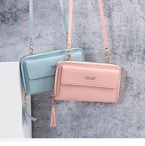 Detail of pink and blue PU leather crossbody bags with tassels and metal chain straps