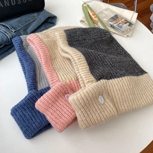Flat lay of knit balaclava hoods with button detail and trendy color block design