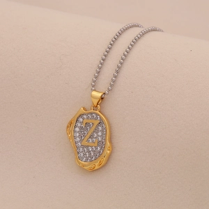 Macro detail of gold letter Z pendant with clear crystals on silver ball chain
