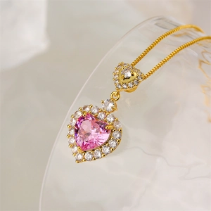 Close-up of gold necklace with double heart pink gemstone pendant and zircon accents