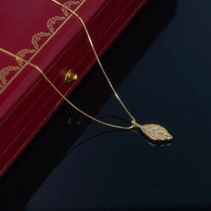 Detailansicht einer goldenen Blatt-Halskette mit Kristallen auf dunkler Oberfläche