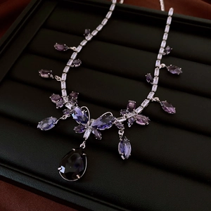 Detail einer Luxuskette mit birnenförmigem lila Edelstein auf schwarzem Display