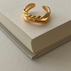 Detail of gold layered open ring with twisted rope texture on an elegant book edge