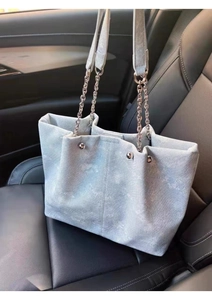 Detail view of light blue floral denim tote bag with silver chain on car seat