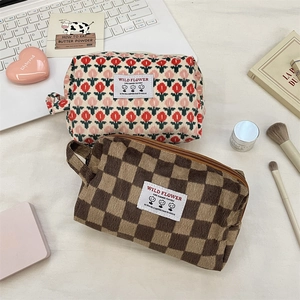 Detail of corduroy cosmetic bags with floral and checkerboard patterns and handle
