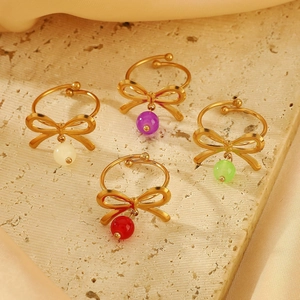 Close-up of four bow-knot adjustable rings with colorful beads on beige stone