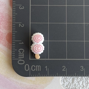Gros plan de miniatures de sucettes roses et blanches de 1,5 cm sur un tapis gradué