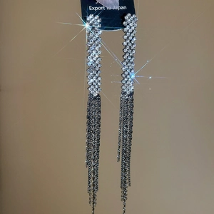 Close-up of sparkling silver tassel earrings with long rhinestone fringes and metal chains