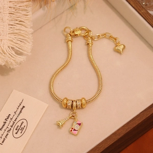 Detailed shot of 18K gold plated snake chain bracelet with Eiffel Tower and camera charms