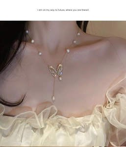 Detail of gold butterfly necklace with shimmering zircon wings and white freshwater pearls