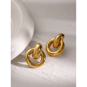 Detail of 18k gold plated interlocking hoop earrings on a minimalist white display