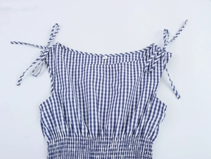 Detail of blue plaid dress showing shoulder tie straps and elastic smocked waist texture