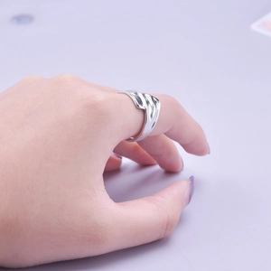 Close-up of a silver adjustable wavy ring made of titanium steel on a purple background