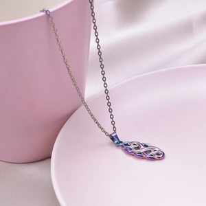 Macro detail of rainbow stainless steel witch knot pendant necklace on pink porcelain