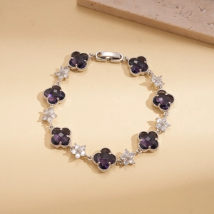 Détails des pierres violettes en trèfle et fleurs blanches sur bracelet argenté