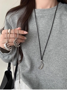 Detail of minimalist leather and metal comb pendants on various chains over a sweater