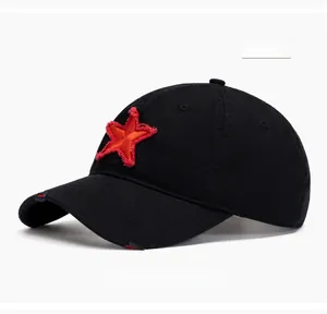 Detail of vintage black baseball cap showing red star patch and distressed brim texture