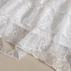 Detailed macro view of white floral lace fabric with layered cake-style tiered embroidery