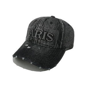 Detailed view of the distressed washed denim texture and PARIS 3D embroidery on the cap