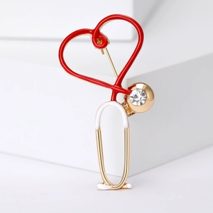 Macro shot of heart-shaped stethoscope brooch with red enamel and sparkling rhinestone