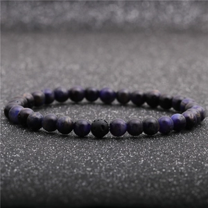 Macro shot of purple tiger eye and black lava stone beads on a glittery black background
