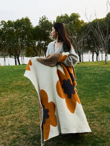 Detailed knit texture of beige sunflower blanket with orange floral pattern