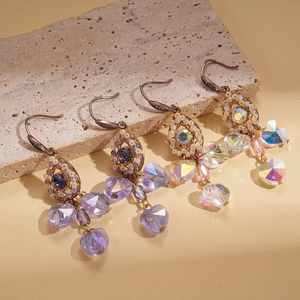 Vintage palace style earrings with purple and clear zircon crystals on beige stone background