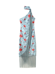 Dettaglio del vestito floreale azzurro con collo asimmetrico e lunghe frange decorative
