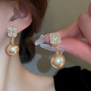 Détail de boucles d'oreilles perles dorées de luxe avec clous en zircon sur modèle