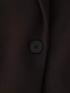 Detail shot of the dark four-hole button and textured wool fabric of the long fringe coat