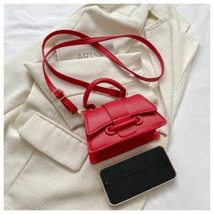 Detail of red PU leather mini square bag with top handle and stitching on a blazer