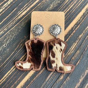 Detail of wooden cowboy boot earrings with leopard cowhide inlay and silver flower studs