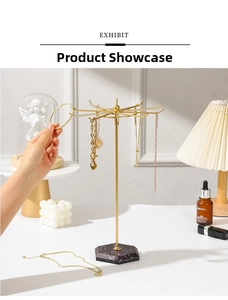 Détail d'un présentoir à bijoux doré pivotant avec socle en marbre dans un décor intérieur