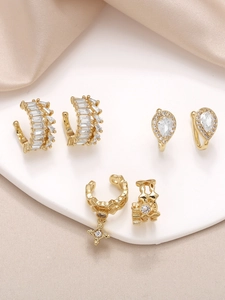 Close-up of gold-plated ear cuff set with cubic zirconia stars on a ceramic tray