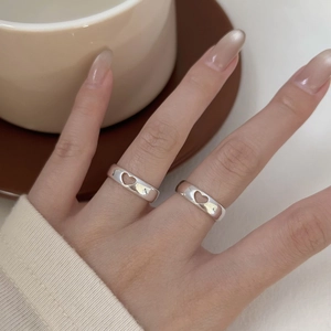 Detailed view of hollow heart silver ring worn by a model in a cozy lifestyle setting