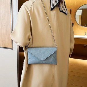 Light blue envelope chain crossbody bag with matte texture shown on shoulder