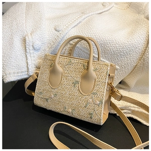 Detail of floral embroidery on a beige straw bag with premium PU leather handle