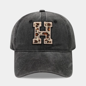 Detail of grey washed canvas baseball cap featuring leopard print embroidered letter H