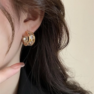 French vintage gold C-shaped hoop earrings with round cubic zirconia on female model