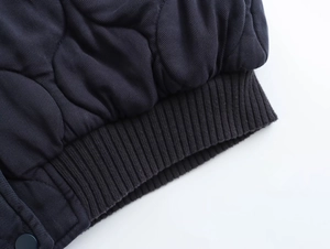Détail du tissu matelassé foncé avec ourlet côtelé et bouton-pression assorti