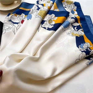 Detailed close-up of twill silk scarf showing floral print texture and satin luster