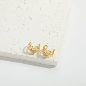 Dettaglio di ear cuff a cuore dorati con lettere LOVE e zirconi su base di pietra bianca