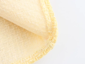 Close-up of yellow tweed fabric showing intricate woven texture and hem stitching details