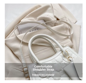 Detail of cream quilted handbag featuring gold hardware and adjustable shoulder strap
