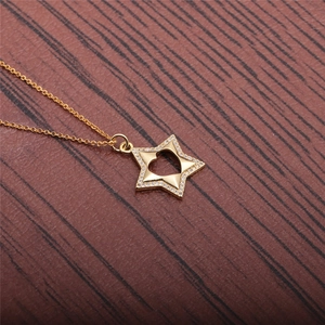 Close-up of gold star pendant with hollow heart and pave zircon on dark wood