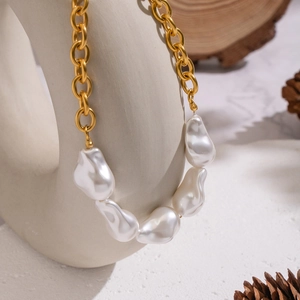 Collier chaîne dorée avec perles baroques sur un support en céramique blanche