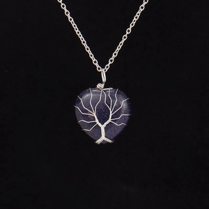 Macro detail of wire-wrapped tree of life pendant on blue sandstone heart necklace
