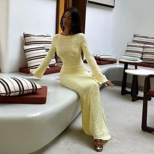 Détail de robe longue jaune clair ajustée avec texture dentelle et manches cloche