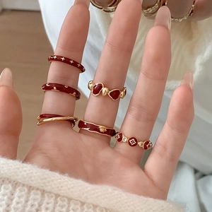 Detail of stacked gold finish rings featuring deep red enamel floral and star motifs