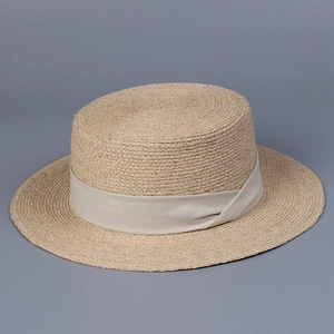 Détail du chapeau de paille en raphia montrant la texture tressée et le ruban crème